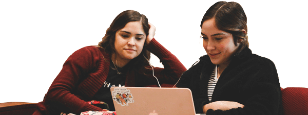 two female students sharing a set of earbuds, smiling and looking at a laptop